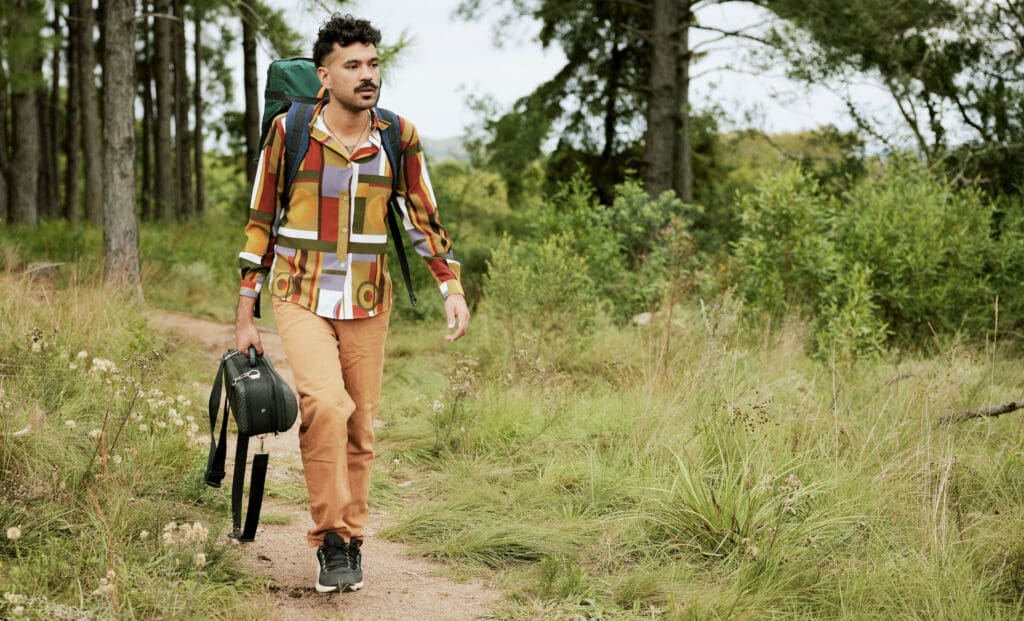 Un homme marchant dans les bois avec un sac à dos à la recherche des meilleures applications pour gagner de l'argent.